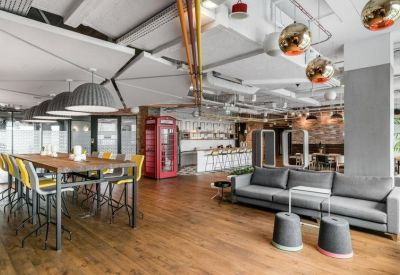 Spacious communal lounge with a grey sofa, wooden floors, and a decorative red phone booth.