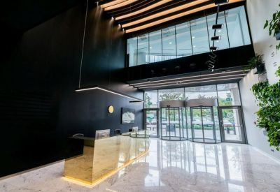 Reception lobby with a sleek wooden desk, marble floors, and a lush vertical plant wall.