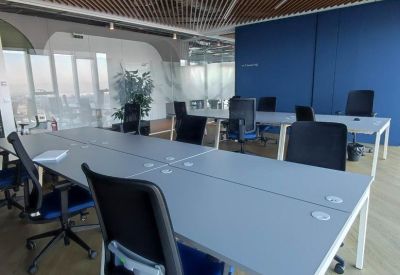 Open-plan workspace with long white desks and a vibrant blue feature wall.