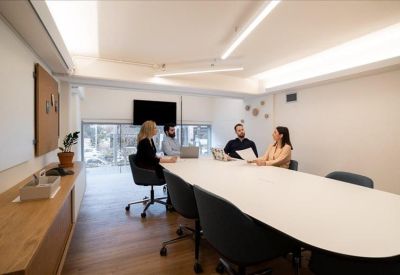 Breakout area with a white bar counter, grey stools and warm wood ceiling.