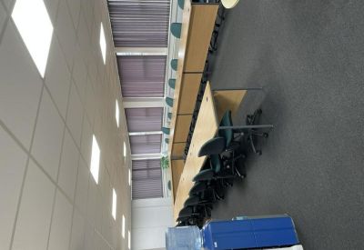 Long training room with rows of wooden desks and black office chairs.