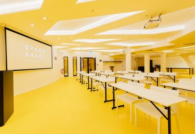 Vibrant auditorium with bright yellow floors and geometric ceiling lights.