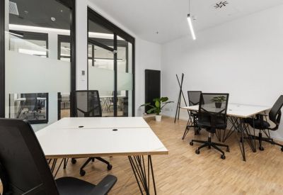 Bright office space with white desks and glass partitioned walls.