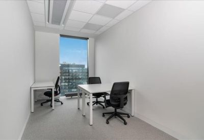 Minimalist private office with two white desks, black ergonomic chairs, and a large window.