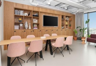 Spacious meeting room with a light wood table, pink chairs, and built-in shelving.
