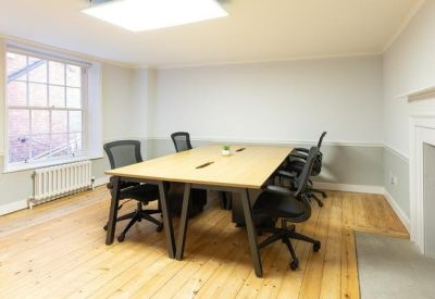 Bright private office featuring a modern wooden desk, ergonomic chairs, and a fireplace.