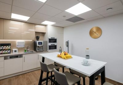 Modern communal kitchen with a dining table, coffee machine, and fruit bowl.