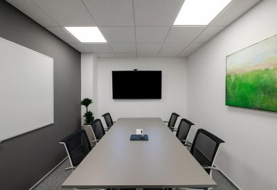 Contemporary meeting room with a long gray table and vibrant green wall art.