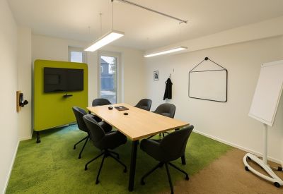 Small meeting room with a black table, grey chairs, and a mobile whiteboard.