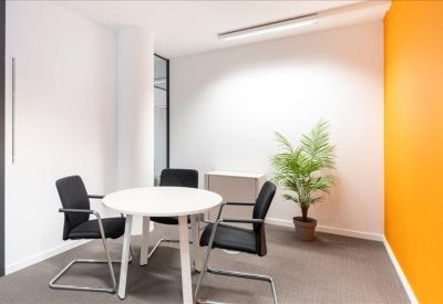 Casual breakout area with a white table, green plant, and orange wall.