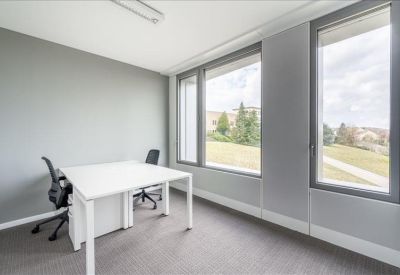 Bright private office with two white desks and large windows.