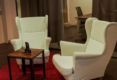 Seating area featuring white wingback chairs on a circular red rug.
