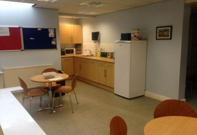 Communal kitchen and break area with wooden cabinetry and dining tables.