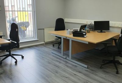 Bright office space with grey wood-effect flooring and modern desks.