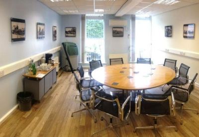 Boardroom featuring a large oval wooden table and black mesh chairs.