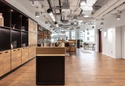 Spacious communal area with warm wood flooring, built-in shelving, and breakout seating.