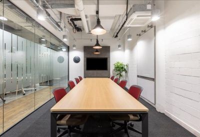 Professional boardroom with a long wooden table, red chairs, and glass partition walls.
