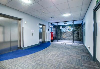 Elevator lobby area with blue carpet accent and glass partition entrance.