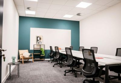 Large boardroom with mesh office chairs and teal accent wall.