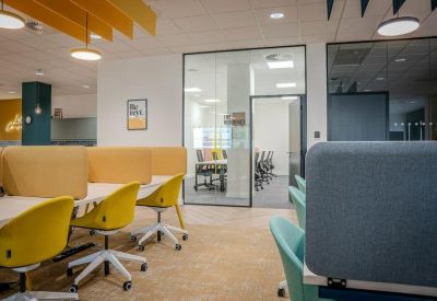 Spacious office area showing workstations with yellow privacy screens and vibrant seating.