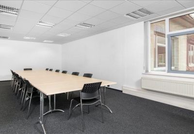 Professional meeting room with a long light-wood conference table and black chairs.