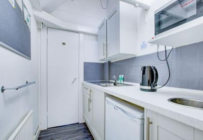 Bright modern kitchen with white cabinetry, a kettle, and a microwave.