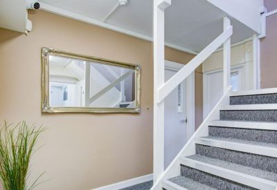 Reception area featuring a staircase with grey carpet and a large gold-framed mirror.