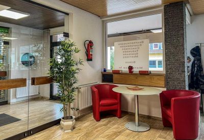 Reception waiting area with two red club chairs and a small round table.