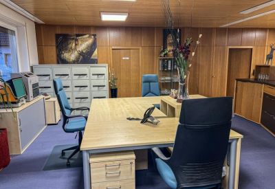 Workstation area featuring wood-paneled walls and a light wood desk with a blue chair.