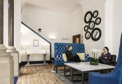 Chic breakout lounge featuring a tufted blue sofa and circular wall mirrors.