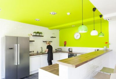 Modern communal kitchen area with vibrant lime green ceiling and walls plus a breakfast bar.