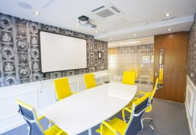 Modern meeting room with a white conference table, yellow chairs, and patterned feature wallpaper.