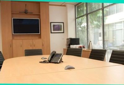 Professional boardroom featuring a large light wood table and wall-mounted television.