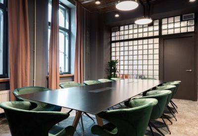 Spacious boardroom with a large black table and green velvet chairs.