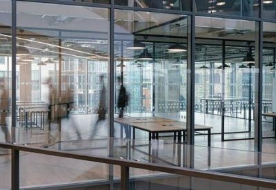 Modern open-plan workspace visible through glass partitions with minimalist wooden desks.