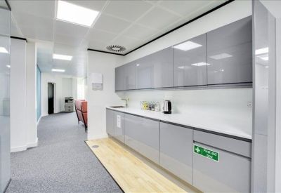 Sleek, modern office kitchen with grey cabinetry and a clean white countertop.