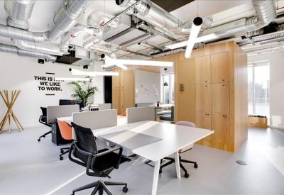 Modern open-plan coworking area with exposed ductwork and industrial lighting.