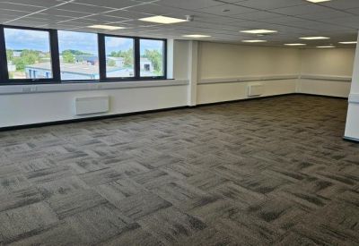 Interior workspace view showing a continuous run of perimeter windows and clean white walls.