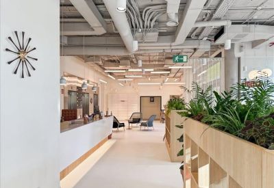 Modern reception lobby with industrial piping and a large sunburst wall clock.