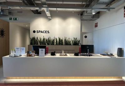 Bright reception area featuring a long white desk and indoor plants.