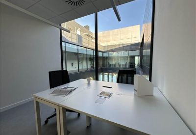 Private office suite with two white desks and views into an internal courtyard.