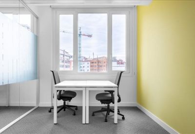 Bright private office for two with a yellow feature wall and large window.