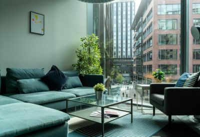 Spacious communal lounge area with teal sofas and large windows offering city views.