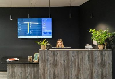 Professional reception desk featuring warm wood textures and a large digital screen.