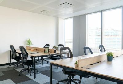 Bright open-plan workspace with multiple desks and potted plants.