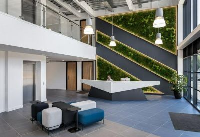 Bright double-height reception area with a geometric front desk and a vibrant diagonal living wall.