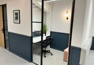 Private single-person workstation pod with a minimalist desk and blue wall panelling.