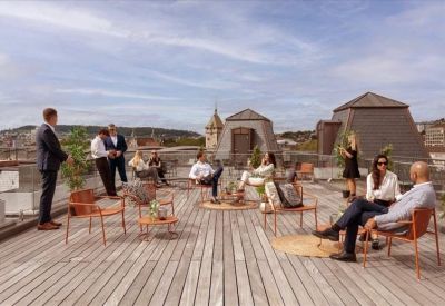 Spacious rooftop terrace with wooden decking and people socializing in lounge furniture.