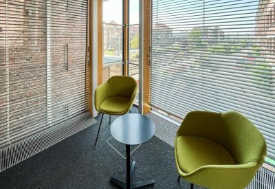 Sun-drenched breakout area with two lime green armchairs and a small circular table.