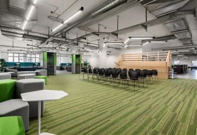 Spacious communal area with green carpeting, tiered wooden seating, and modern light fixtures.